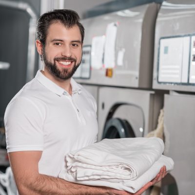 dry cleaning worker holding stack of clean clothes